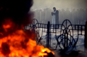 A priest prays in front of riot police during clashes with anti-government protesters in Kiev
